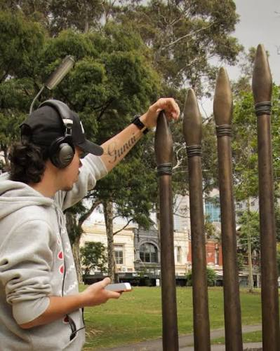 A visitor with headphones touching the bronze spears of the Yalinguth audio walk installation.