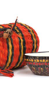A woven First Nations bag with ochre and charcoal stripes alongside a hand-painted wooden bowl.